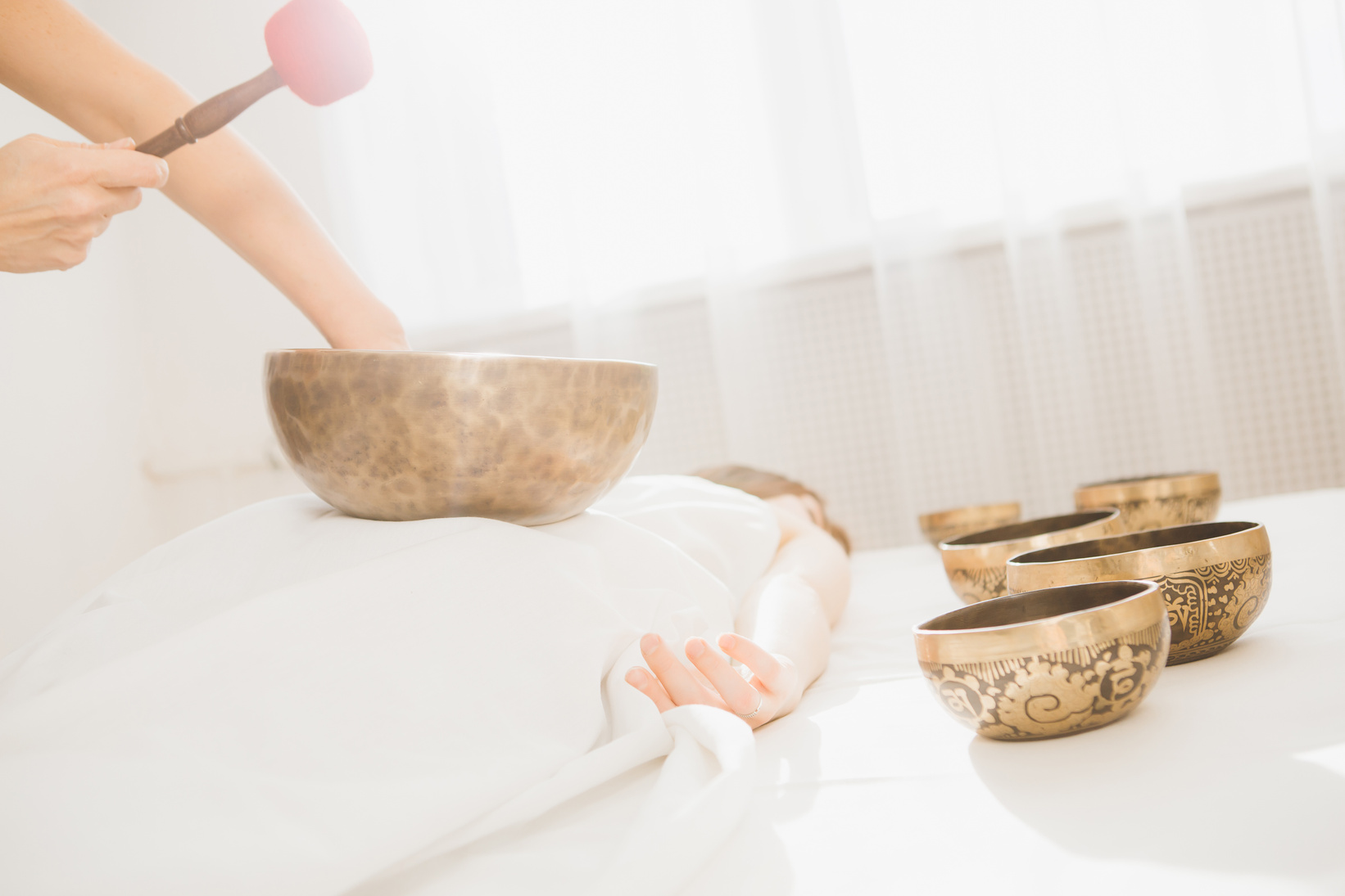 Girl doing massage therapy singing bowls in the Spa